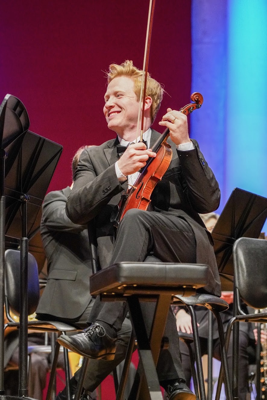 Adam Moore performing violin in an orchestra